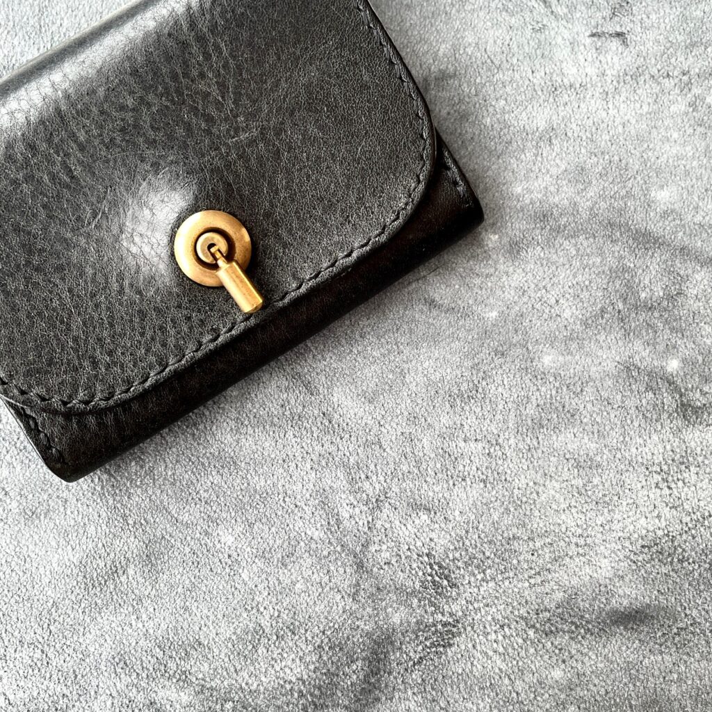 使用前の革の上に置かれた、エイジング後の黒い名刺入れ。
